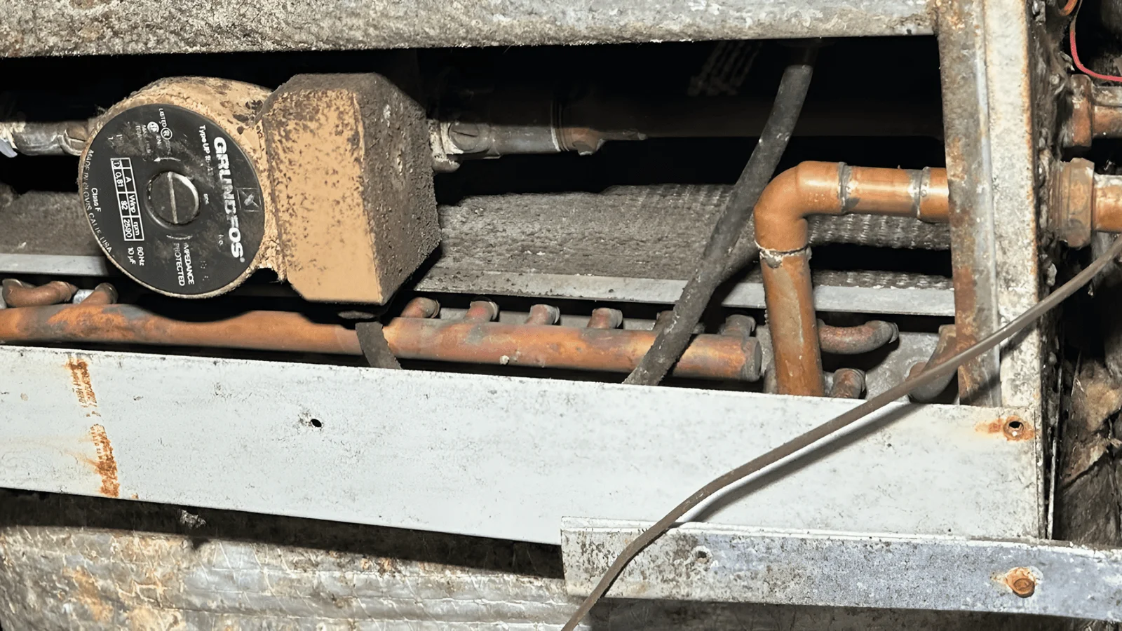 New furnace unit with copper piping, circulation pump, and ductwork connections installed in mechanical space